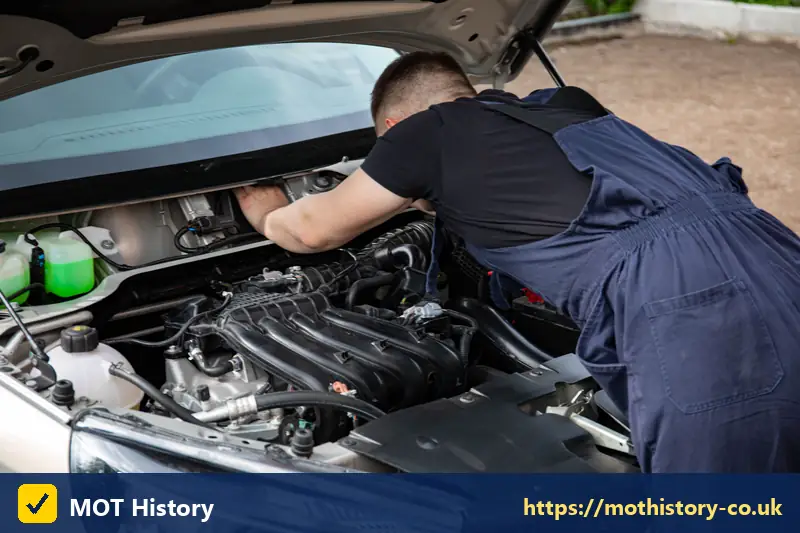 Mechanic working on a car engine in daylight - bhp check by reg