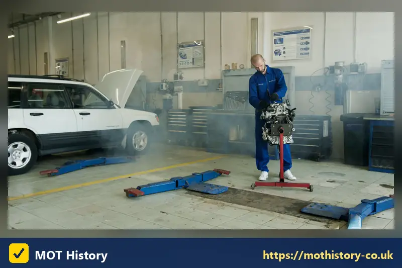 Mechanic lifting an engine on a workshop stand - check sorn car