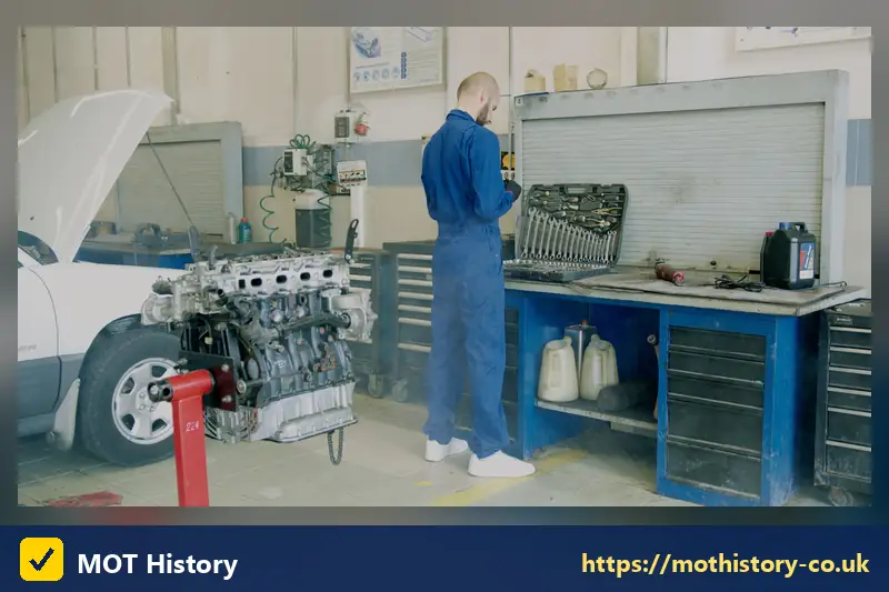 Mechanic beside an engine on a workshop bench - check vehicle mot history