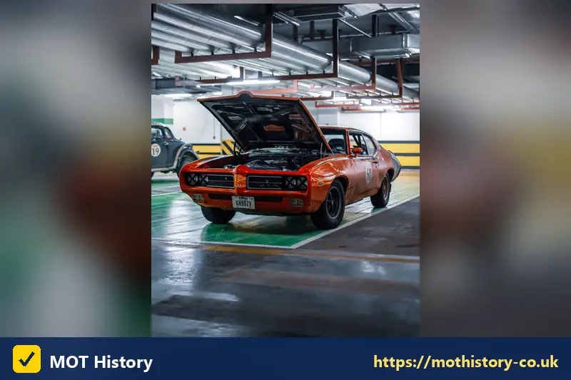 Classic orange muscle car in a garage with the bonnet up - cherished reg