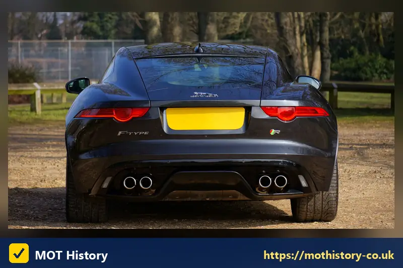 Rear of a dark coupe with a yellow number plate - d reg year