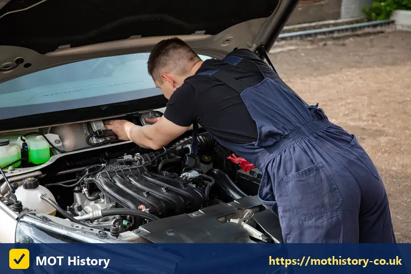 Mechanic checking a car engine with the bonnet raised - gasoline check