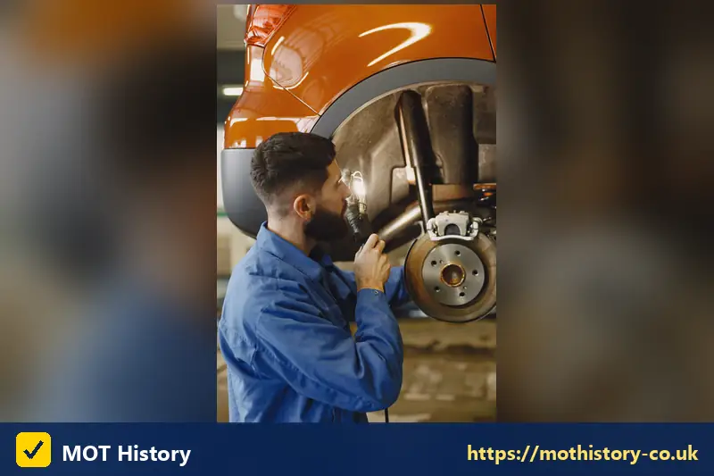 Mechanic inspecting a brake disc and suspension - hgv mot history