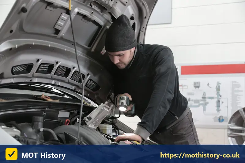 Mechanic inspecting an engine with a torch - ireland mot check