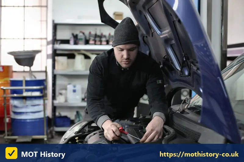 Mechanic working on a blue car engine in a garage - is my car lez compliant