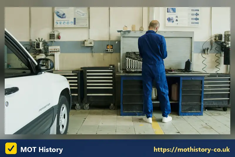 Mechanic at a workbench beside a white car in a workshop - my car needs a
