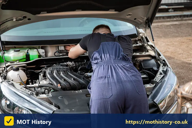 Mechanic inspecting an engine under a raised bonnet - new car first mot