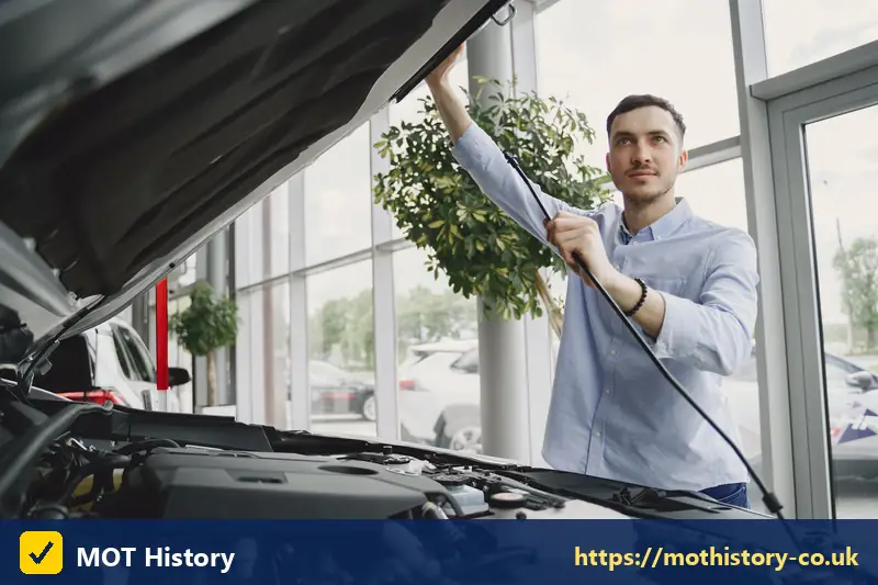 Man checking under the bonnet of a car in a showroom - new driver auto insurance