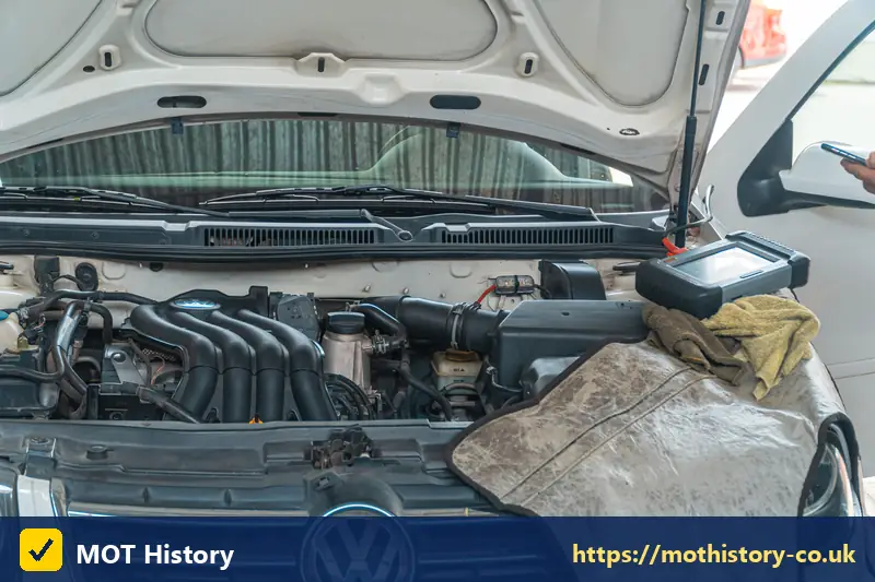 Diagnostic tablet on the engine of a white car - non comprehensive insurance