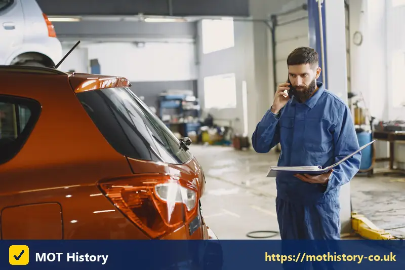 Mechanic with a clipboard on the phone in a garage - specs by reg