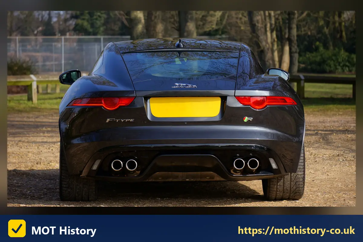 Rear of a dark coupe with a yellow number plate - show reg plates